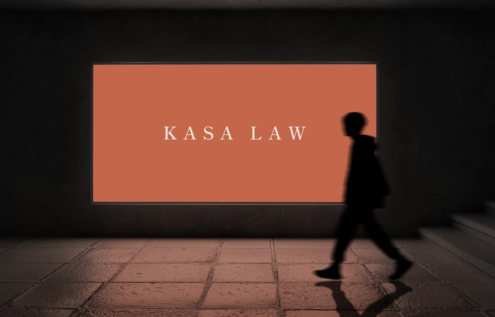 A Kasa Law billboard in an underground walkway, a figure walking past